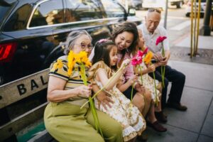 A multigenerational family sitting outdoors, highlighting the idea of living with aging parents