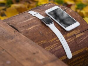 An iPhone and a fall detection watch for seniors on a log