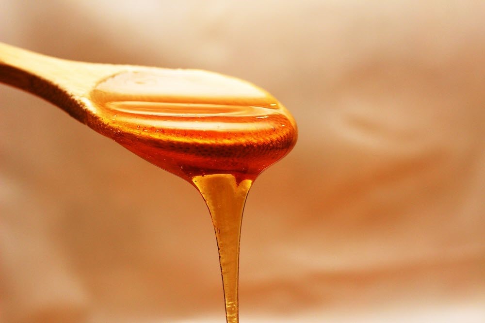 Honey pouring from a wooden spoon