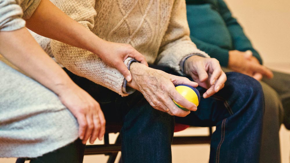 A caregiver holding a seniors hand, highlighting the idea of caregiving as a profession