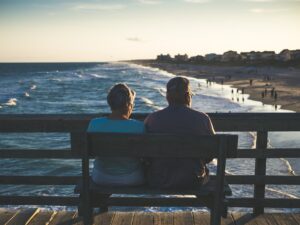 A man and woman sitting looking at the ocean, highlighting questions of caring versus selfishness