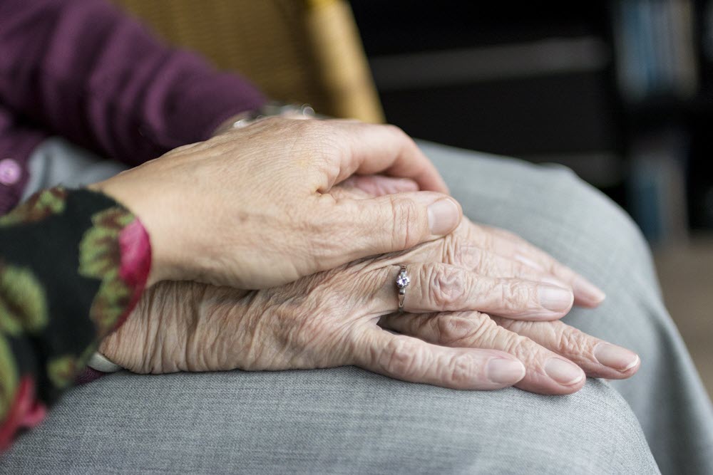 A senior holding another hand, highlighting the idea of therapy or of supporting one another