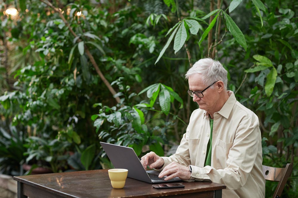 A senior using a Mac sitting outside