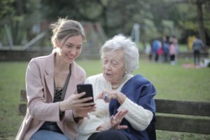An elderly woman talking to her granddaughter or another family member about something on her phone