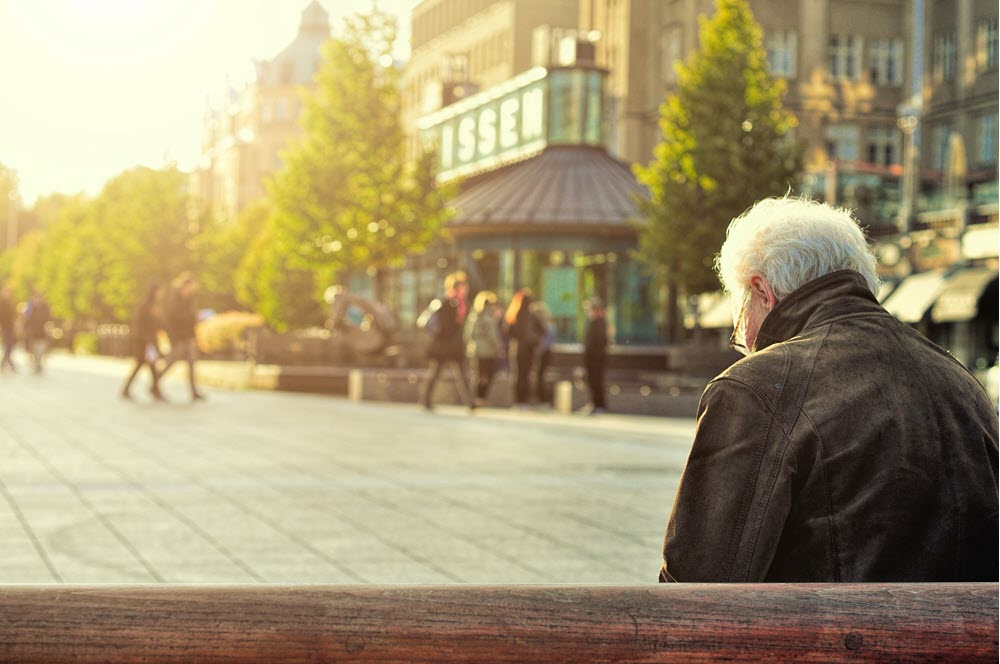 A sad or peaceful man sitting outside, possibly with dementia, highlighting the idea of trying to keep dementia patients from wandering