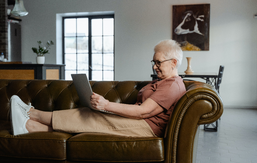 A senior sitting on the couch looking at a laptop