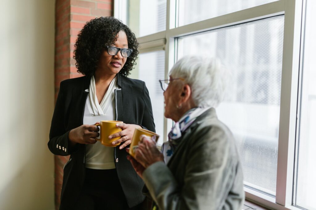 An older woman and a professional woman having a conversation, perhaps about dementia