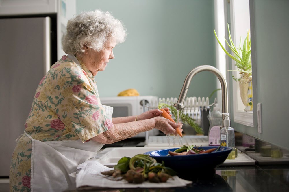 A senior woman washing carrots, highlighting the importance of home appliances for seniors