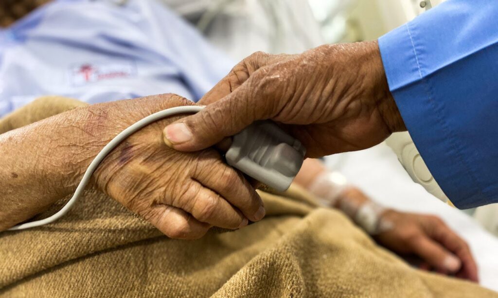 An older man holding a womans hand, highlighting the idea of advocating for a loved one in hospital