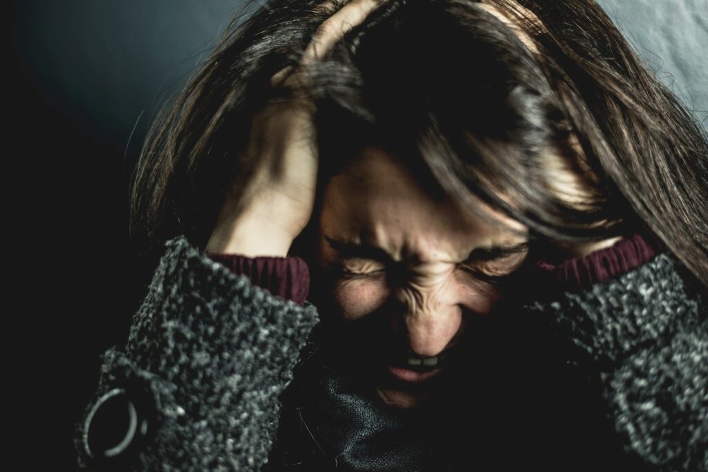 A woman with her head in her hands, highlighting the idea of completing the stress cycle