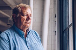 An angry senior looking out of a window