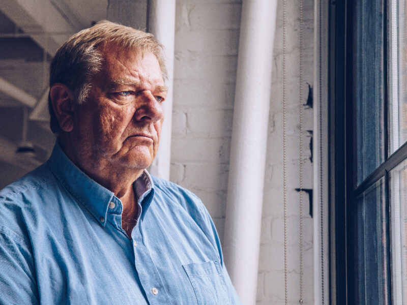 An angry senior looking out of a window