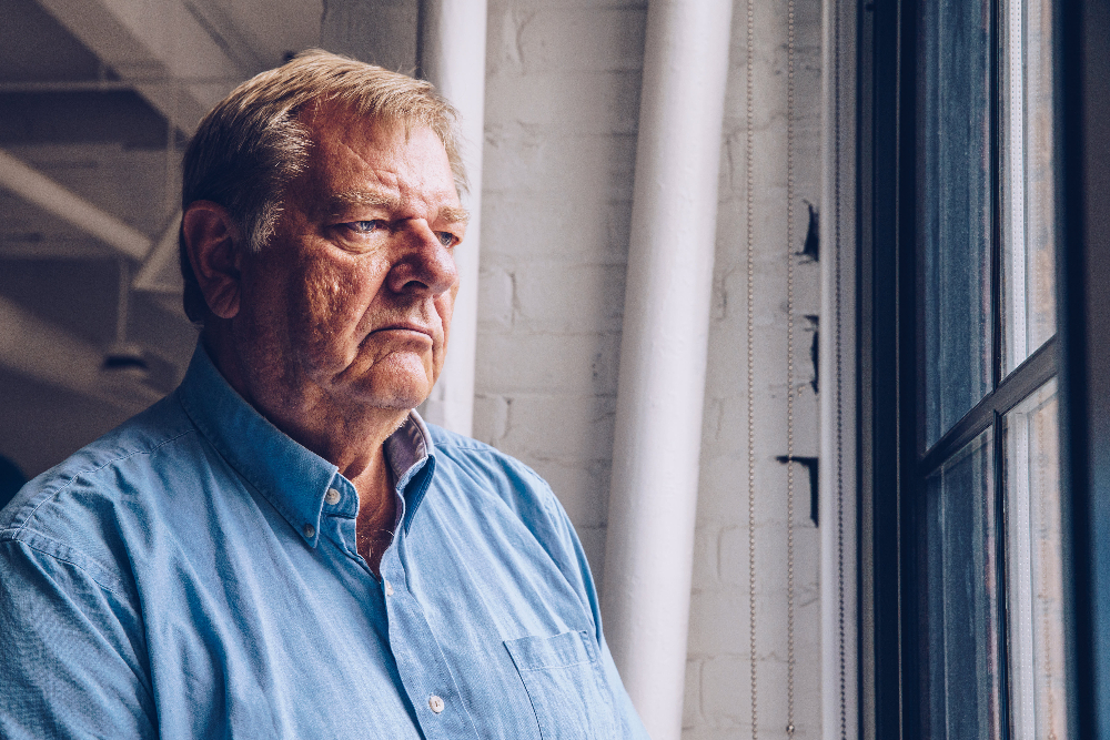 An angry senior looking out of a window, highlighting the question of why do older people get mean