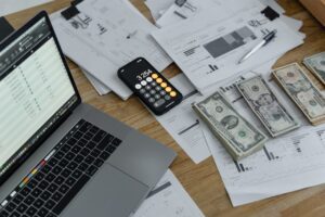 A calculator and some money next to a laptop, highlighting the idea of saving money or balancing accounts