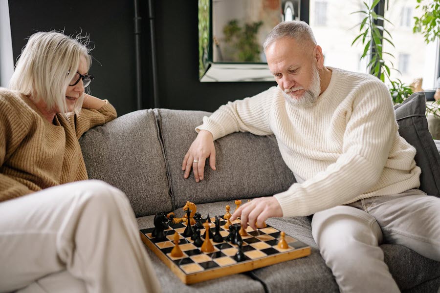 A couple sitting on the couch playing chess