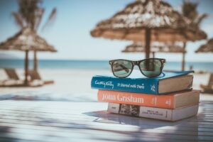A small pile of books topped with sunglasses, as an illustration for some of the best vacations for seniors with limited mobility.