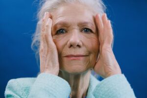 A woman holding her hands to either side of her face, perhaps wearing contacts