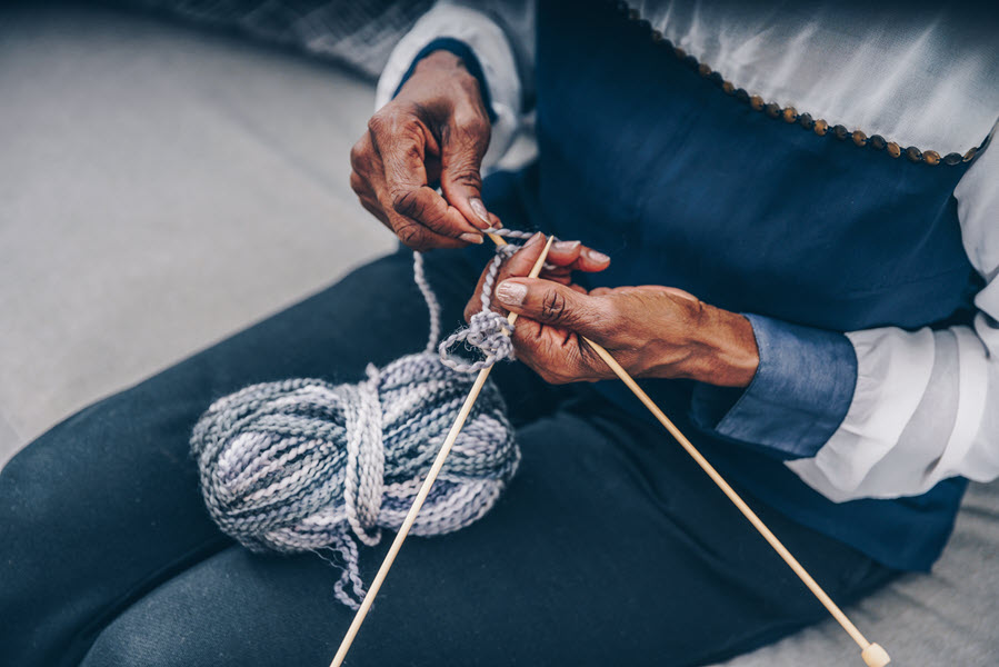 A woman knitting with yarn in her lap