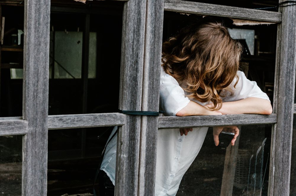 A woman looking out a window, highlighting the idea of learning to sit with discomfort