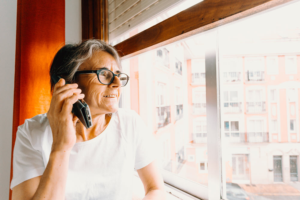 An elderly woman on the phone looking out the window