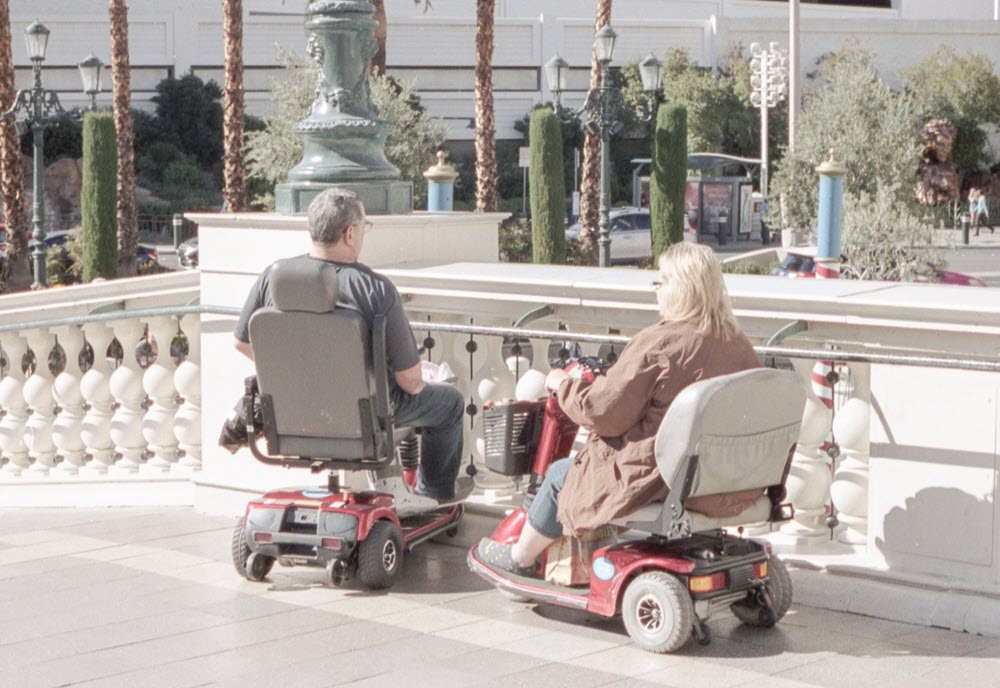 Two seniors in mobility scooters on vacation