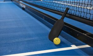 A pickleball racket and ball against a net