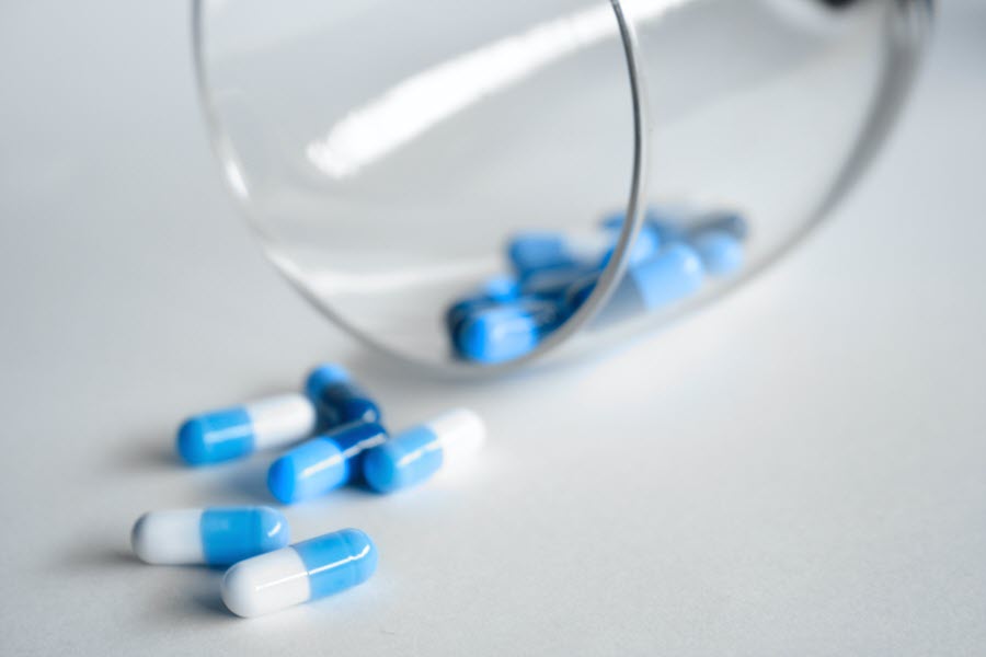 Blue and white pills spilling out of a glass, highlighting the idea of dementia medication abuse