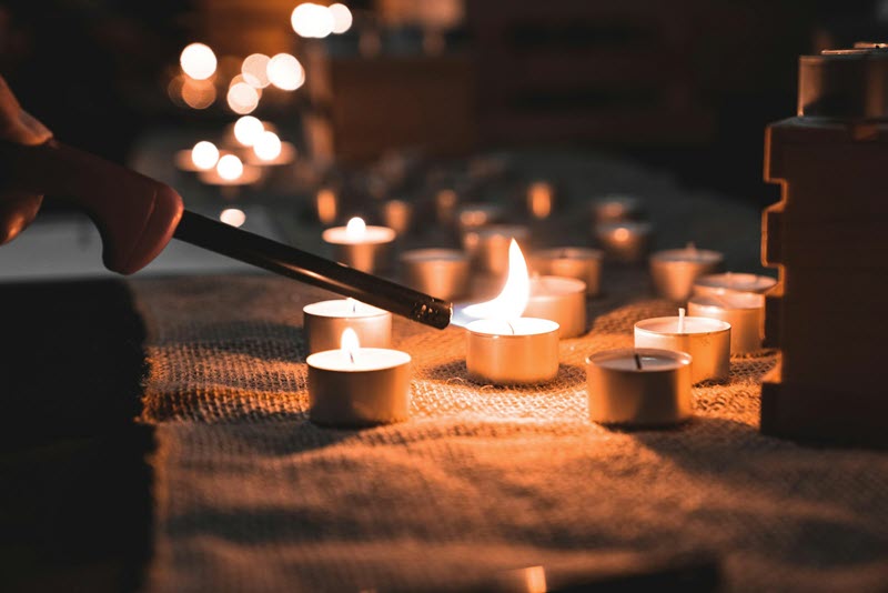 Lighting a collection of tealight candles in remembrance, highlighting the idea of dementia and spirituality 