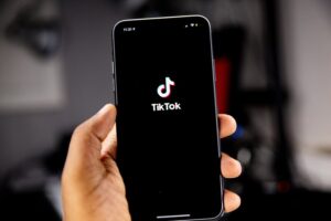 Someone holding an Apple phone with the TikTok app loading
