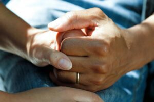 Two people holding hands, highlighting the idea of caregiver support