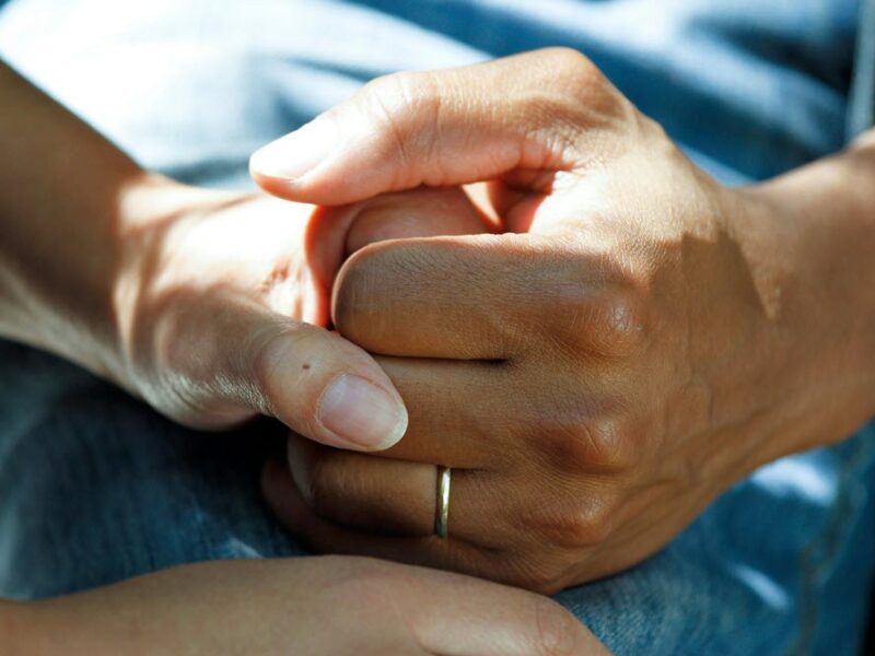 Two people holding hands, highlighting the idea of caregiver support