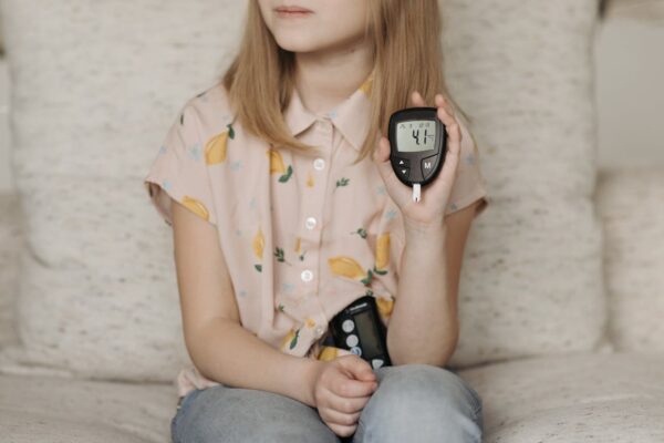A girl with a glucose monitor and a blood testing strip