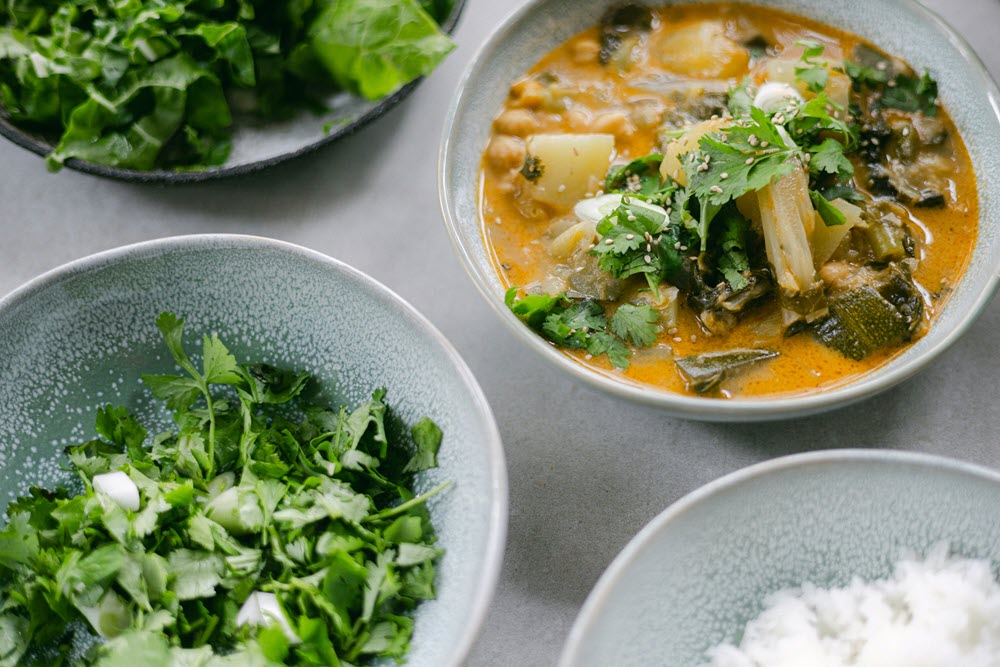 Three bowls of food. One contains an authentic meal, one some greens, and another rice