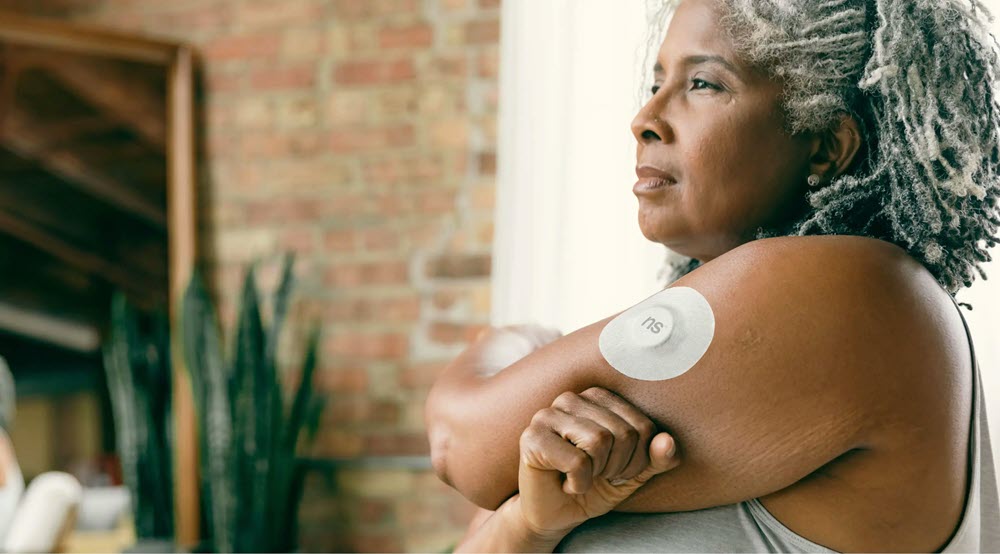 A woman with a glucose monitoring patch on her arm, highlighting the idea of Dexcom G7 Medicare coverage